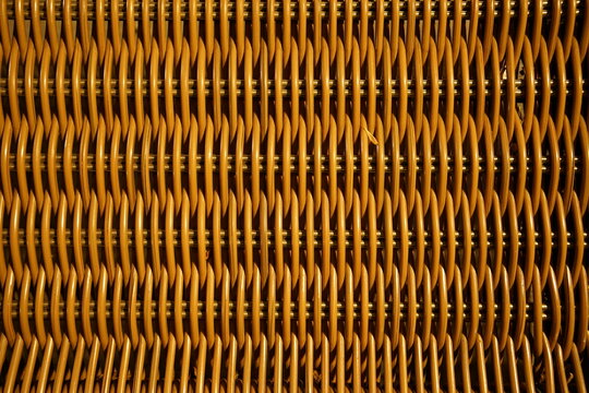 Close-up view of woven wicker material forming a repeating geometric pattern. Detailed texture of a bench.
