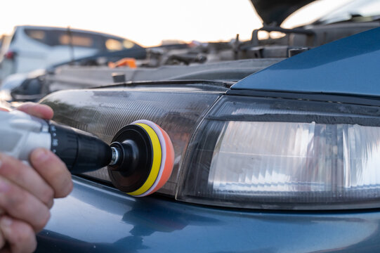 The process of polishing car headlights outdoors. 