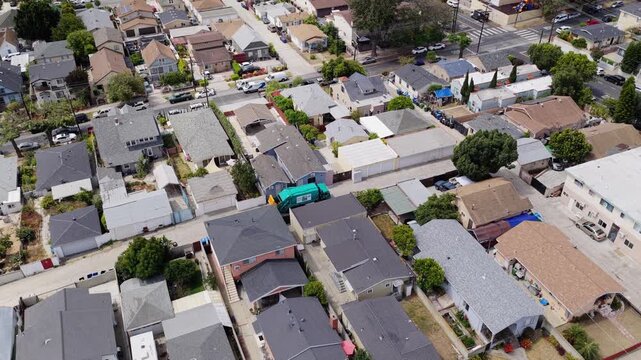 Aerial top down inspection of a low income neighborhood with small homes, trees, cars and streets in south central Los Angeles, California
