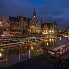 Fototapeta premium Bruges is a museum, Brussels is a meeting, but Ghent is a party! Ghent city centre at night with boats and reflections in the canal river water. 