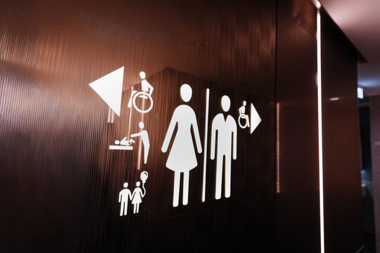 Signage indicating restroom facilities with symbols for male, female, family, and accessible options on a modern wall in a public building