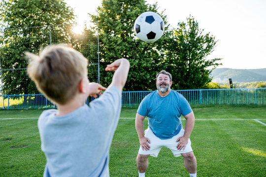 Father teaching son football skills during training on sports field.