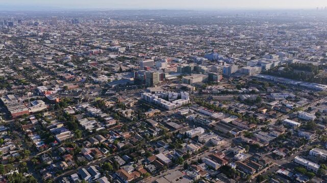 Urban sprawl in Los Angeles, California, with cityscape featuring residential houses, commercial buildings, green trees, downtown skyscrapers on a sunny day