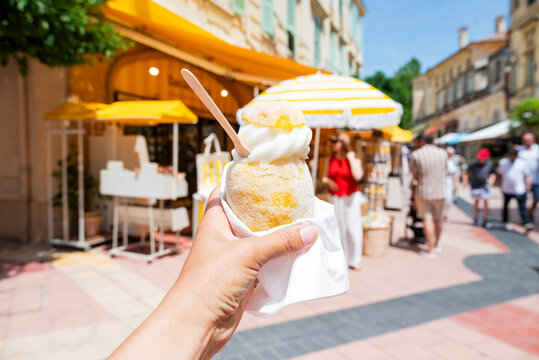Close-up of a refreshing lemon sorbet ice cream being held in hand on a sunny street in Menton, French Riviera.