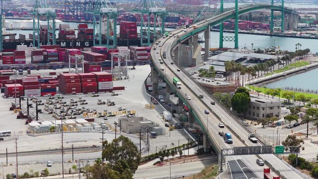 Vincent Thomas Bridge connecting San Pedro to Terminal Island at Port of Los Angeles with heavy highway traffic over commercial shipping cargo container terminal