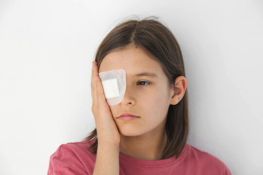 girl with medical eye patch covering injured eye, standing light background,  ophthalmology treatment, eye injury recovery, healthcare, pediatric medicine, vision protection, rehabilitation concept