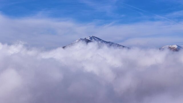Epic aerial forward motion over frozen alpine mountain range with sharp snowy summits under clear sky.