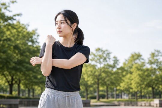 芝生の前で肩を伸ばすスポーツ女性