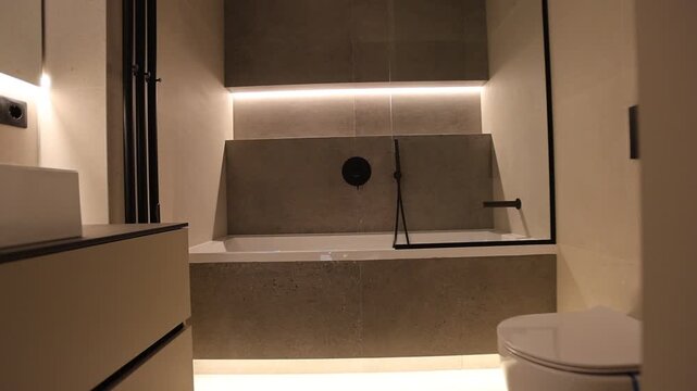 Minimal modern bathroom interior with wall mounted sink and warm cabinet lighting