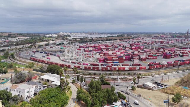 Long cargo train traveling through busy Port of Los Angeles container terminal showing import export supply chain industry and logistics hub with shipping containers