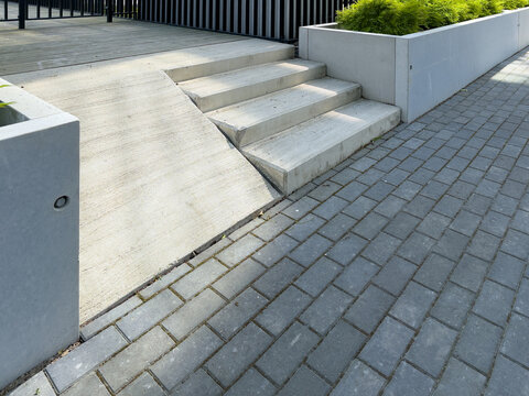 Concrete entrance ramp beside stairs at modern apartment building for barrier free access