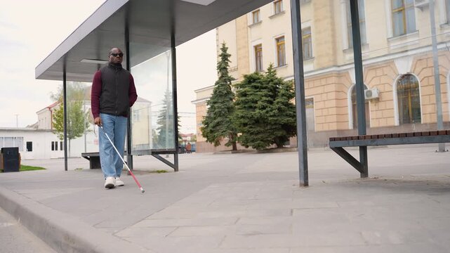 Blind African American man navigating city street with white cane