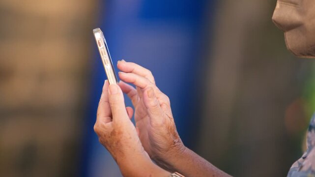 Slow motion senior Taiwanese woman uses a smartphone on a Tamsui street at night, showing older adult adaptation to modern technology, communication, urban life and digital connection