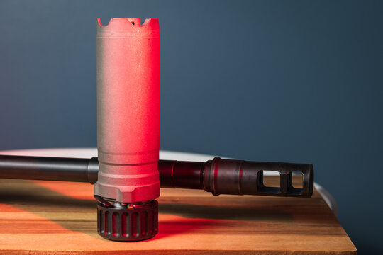 Rifle Suppressor and Muzzle Brake on Firearm Barrel under Cinematic Red Neon Light, Gun Silencer and Tactical Attachment Detail