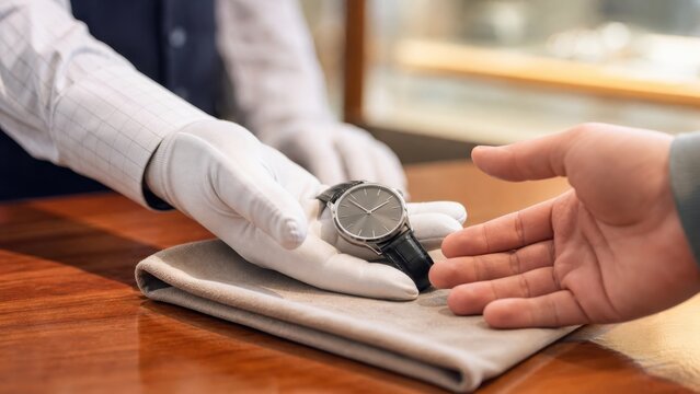 腕時計を手渡して査定を受ける手元