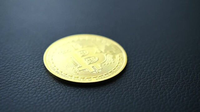 Golden bitcoin coin on dark textured surface shows cryptocurrency logo