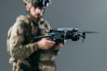 Fototapeta premium Military serviceman in camouflage uniform operating a UAV drone with remote control device. Concept surveillance, defense technology and operational control. 