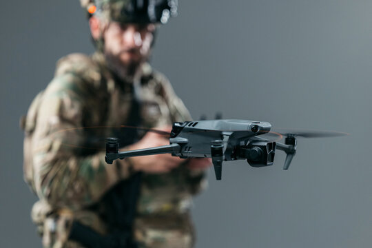 Tactical soldier piloting unmanned aerial vehicle using handheld controller in controlled environment. Concept military UAV systems, reconnaissance and security.

