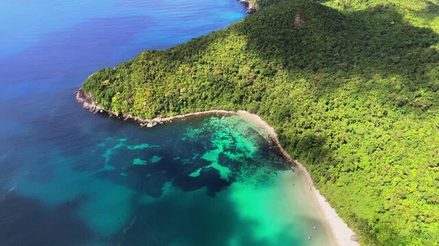 Vertical aerial drone view of two small sandy coves set into a rugged rocky jungle coastline with turquoise and deep blue water, Catpo Beach, Liminangcong, Taytay, Palawan, Philippines.