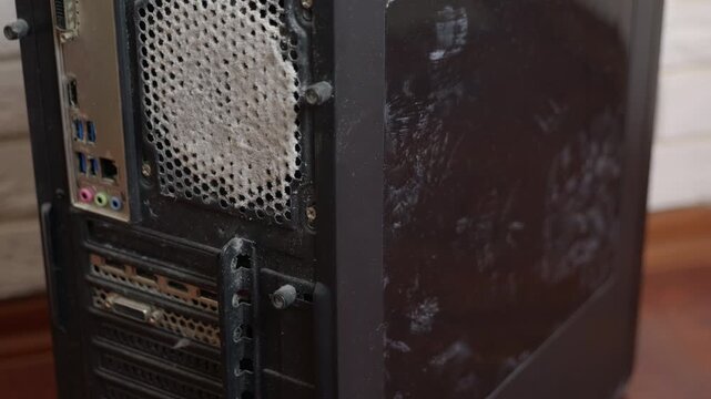 Very dusty computer case needs cleaning. Close-up view of the back of a black desktop computer tower, showing the power supply unit fan vent heavily clogged with a thick layer of dust