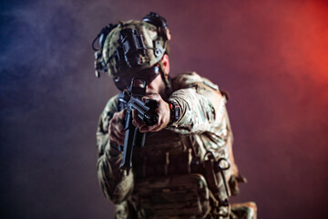 Obraz premium Modern soldier wearing camouflage combat equipment and night vision goggles while holding rifle. Concept security, protection and military profession. 