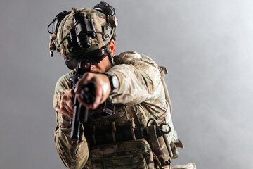 Obraz premium Soldier in camouflage tactical gear holding rifle and wearing night vision goggles on isolated background. Concept military equipment, defense and security. 