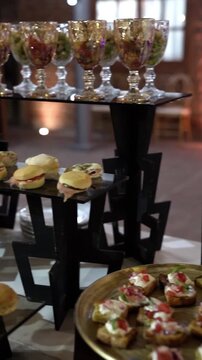 Close-up of a catering reception table featuring rows of mini bagels and sandwiches at an elegant outdoor nighttime event.	
