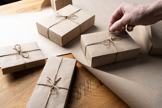 Woman adjusting bow on wrapped Christmas gift box with kraft paper packaging
