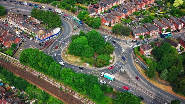 Drone footage of a busy roundabout and railway line in Salisbury, Wiltshire, England. The aerial view shows moving traffic, buses, cars, residential streets, train tracks