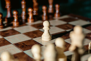 Wooden chess knight surrounded by pawns and other pieces on a chessboard. Symbol of strategy, tactical thinking, leadership, and competitive planning. © Yegor