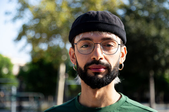 Headshot portrait of young caucasian man outdoors looking at camera with serious expression.