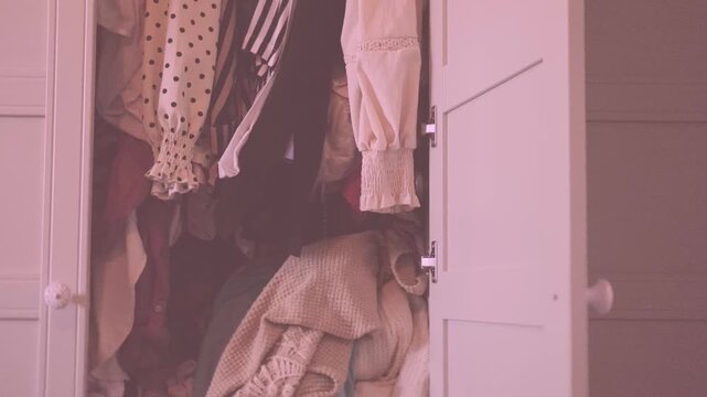 overcrowded wardrobe packed with clothes hangers, excess garments limited space, messy storage, decluttering, overconsumption lifestyle hoarding behavior accumulation, organization mental overload