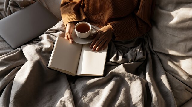 Woman with journal and tea in cozy bed