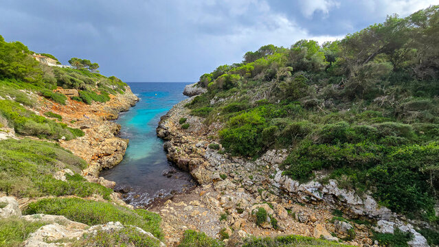 Beautiful landscape of Cala Murta bay with turquoise water and rocky cliffs under cloudy sky in Mallorca, Spain