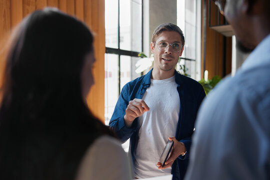 Business professional leading a collaborative meeting, using hand gestures to present ideas and plan strategy with a diverse team in a modern coworking office space