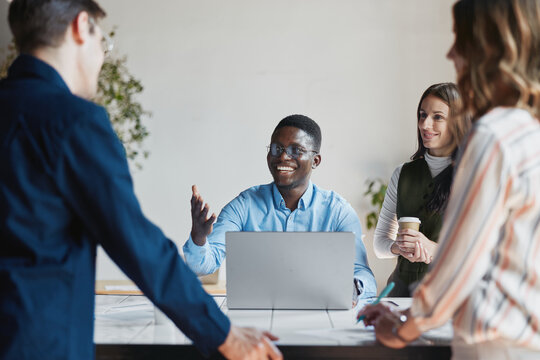 Diverse startup team collaborating during a business meeting. An african american man smiling and actively participating in discussion. Presenting ideas to colleagues