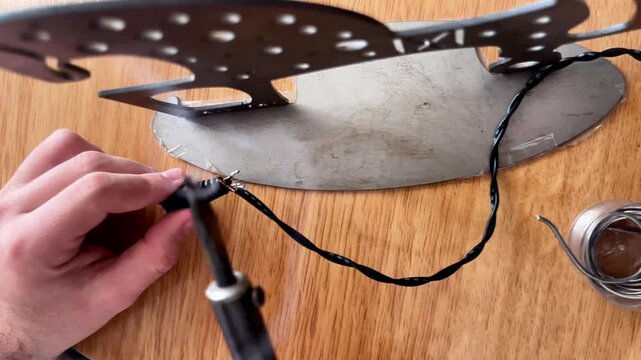 Technician soldering electrical wire to connector with soldering iron
