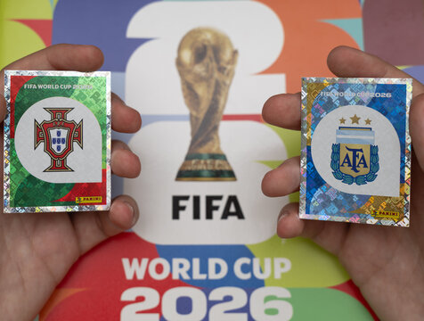 hands holding shiny panini stickers of portugal and argentina football crests for the fifa world cup 2026 tournament background