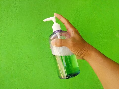 A hand holding a bottle of hand sanitizer.