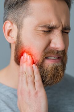 Man Experiencing Intense Jaw Pain and Discomfort, Holding His Cheek with Red Inflammation Highlight