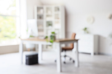 Fototapeta premium Blurred view of light office with modern workplace, shelf unit and green plants