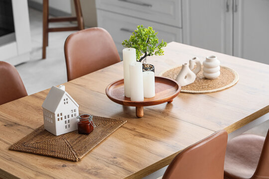 Wooden dining table with houseplant and candles in interior of kitchen, closeup