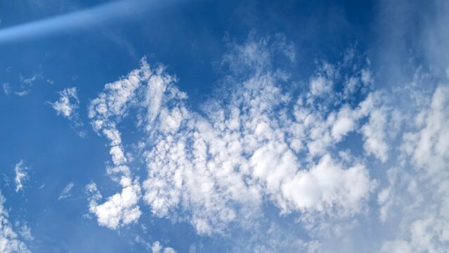 a bright blue sky filled with scattered, light white clouds, frequently categorized as a "cloudy sky".