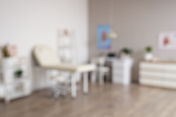 Fototapeta premium Blurred view of medical office with couch, shelf units and doctor's workplace