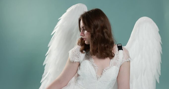 Beautiful girl with angel wings on light blue background, camera moving up
