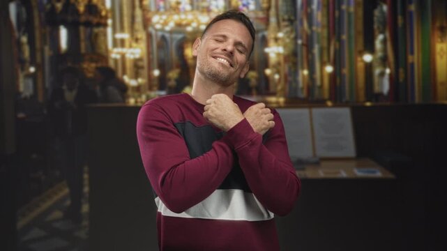 Man forming heart with hands and smiling, tattooed wrist visible inside ornate church building with chandeliers; affection connection bond.