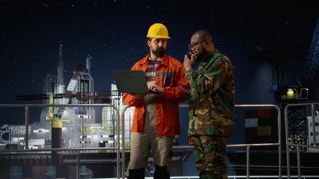 Military man on drilling rig speaks into walkie talkie, enforcing blockade protocol while a soldier on offshore platform talks in handheld radio to receive update on war causing oil crisis.