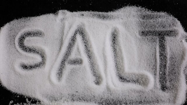 salt crystals spelling word salt on dark background with seasoning concept