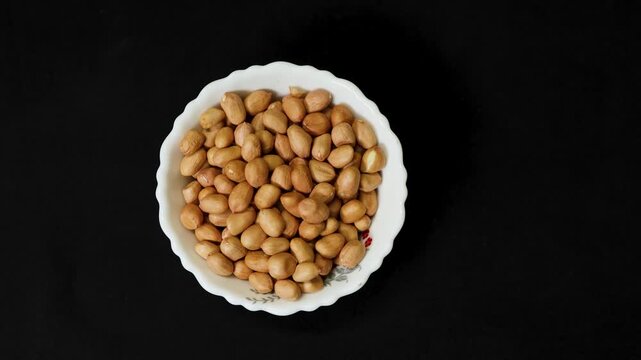 raw peanuts in white bowl isolated on black background healthy snack concept