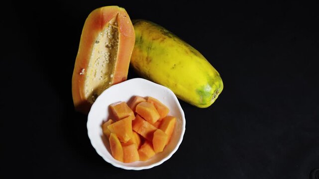 fresh papaya pieces in bowl alongside whole ripe fruit rich in vitamins